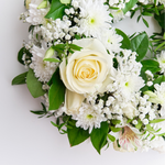 Floral arrangement with white roses and green leaves on a light background