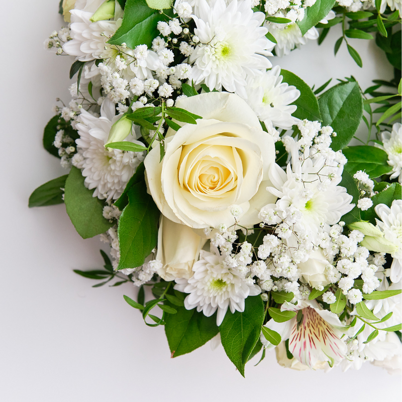 Floral arrangement with white roses and green leaves on a light background
