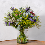 Close up of Wild and Wonderful bouquet showing waxflowers, purple statice and seasonal foliage wrapped in natural recycled burlap