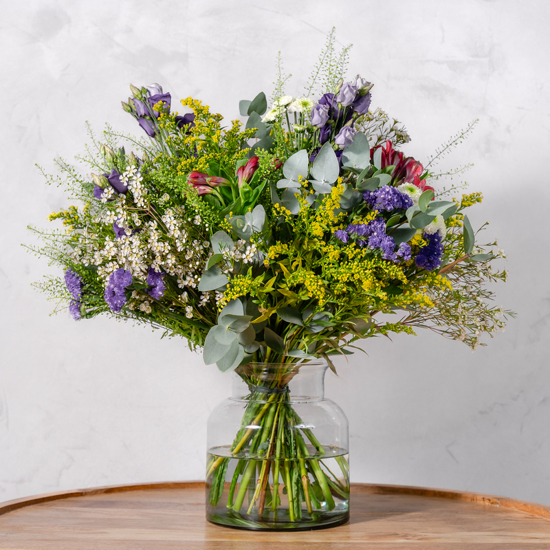 Close up of Wild and Wonderful bouquet showing waxflowers, purple statice and seasonal foliage wrapped in natural recycled burlap
