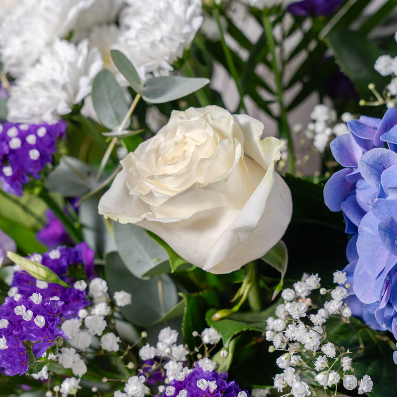 Side view of Blue Moon blue and purple flower bouquet with phoenix palm leaves and salal available for same-day Dublin delivery