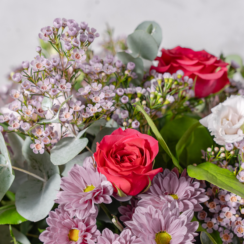 Close up of Pretty in Pink bouquet showing pink roses, gerbera and lisianthus with phoenix palm leaves and eucalyptus