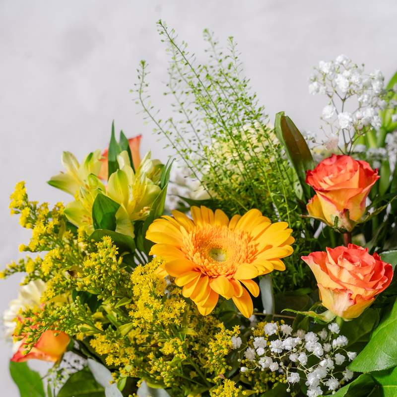 Close up of You're So Golden bouquet showing yellow roses, gerbera and lilies with gypsophilia and eucalyptus